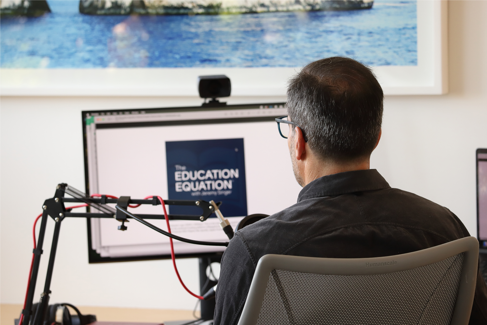 Jeremy Singer, host of The Education Equation, faces his computer with the Education Equation logo visible.