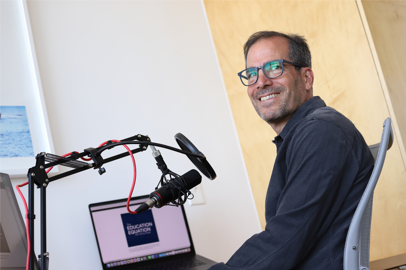 Jeremy Singer, host of The Education Equation, sitting at this recording station looking off camera.